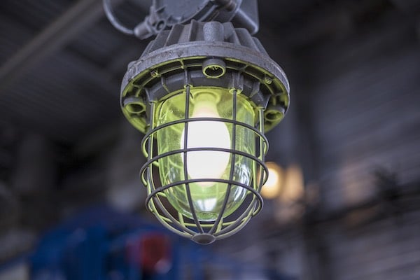 Compare and contrast intrinsic safety with explosion-proofing. Pictured: a close-up of an explosion-proof lamp in an industrial facility